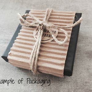 Pu&ograve; includere: Una piccola scatola rettangolare avvolta in carta marrone con un fiocco di spago. La scatola ha un bordo nero e un'etichetta che recita "Fabricacion Artesanal".