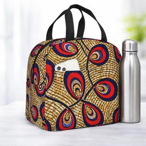 May include: A patterned lunch bag with a black handle and a side pocket holding a white phone. The bag features a repeating design of red, blue, and yellow teardrop shapes. A silver water bottle sits next to the bag.