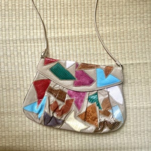 May include: A beige leather shoulder bag with a patchwork design. The bag is made of different colored leather pieces, including red, pink, blue, green, brown, and white.