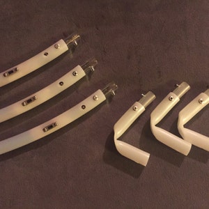 May include: Five white plastic pieces with silver accents. Three pieces are curved and two pieces are bent at a 90-degree angle.