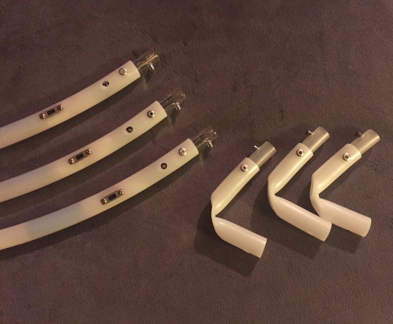 May include: Five white plastic pieces with silver accents. Three pieces are curved and two pieces are bent at a 90-degree angle.
