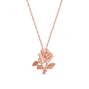 Puede incluir: Un collar de oro rosa con un colgante de rosa. La rosa est&aacute; detallada con hojas y un tallo.