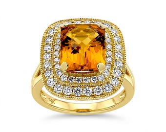 Pode incluir: Um anel de ouro amarelo 14K com uma grande pedra preciosa citrino laranja de corte almofada no centro. O citrino é rodeado por um halo duplo de pequenos diamantes brancos redondos cravados em ouro, com um detalhe de borda milgrain.
