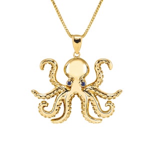 May include: A gold octopus pendant necklace with blue sapphire eyes. The octopus is detailed with textured tentacles and a smooth body.