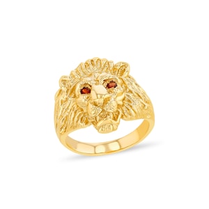 Könnte beinhalten: Ein goldfarbener Ring mit einem detaillierten Löwenkopf-Design. Der Löwe hat eine strukturierte Mähne und zwei kleine, rote Edelsteinaugen. Der Ring ist ein auffälliges Schmuckstück für verschiedene Anlässe.