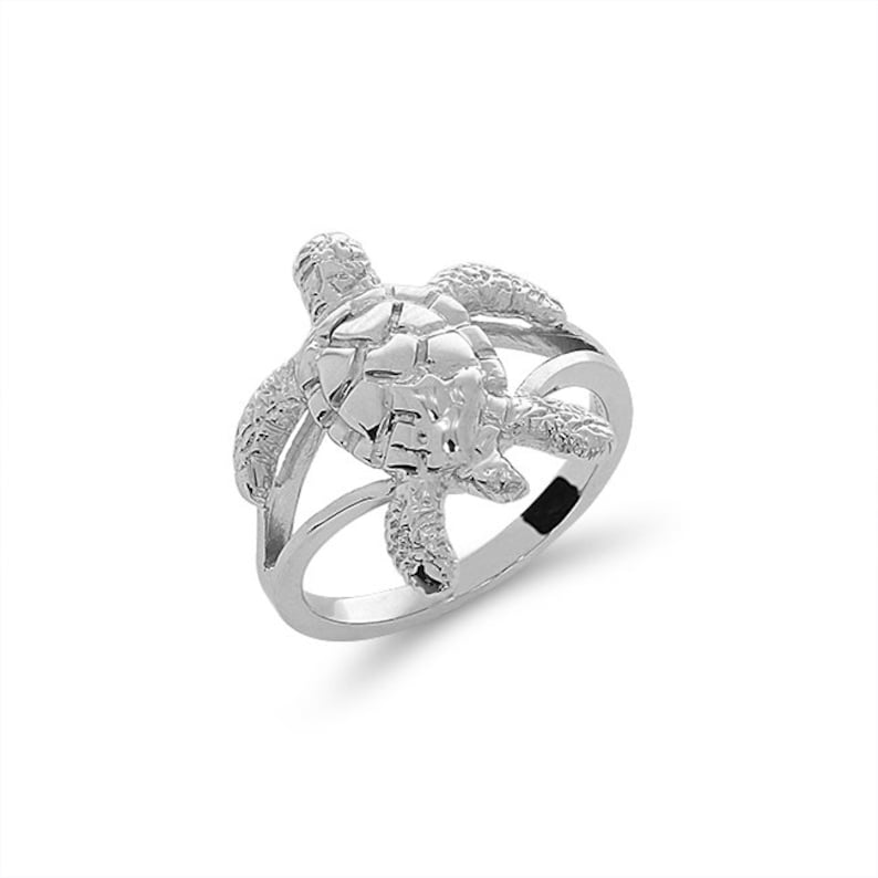 May include: A silver ring featuring a detailed turtle design. The turtle is positioned on top of the ring band, with its head and legs extending out.