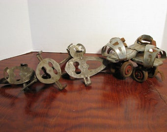 May include: A set of vintage roller skate attachments. The set includes two metal skate frames and a pair of roller skates with leather straps and metal cages. The skates have red wheels.