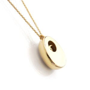 May include: A gold chain necklace with a round pendant. The pendant has a small opening in the center.