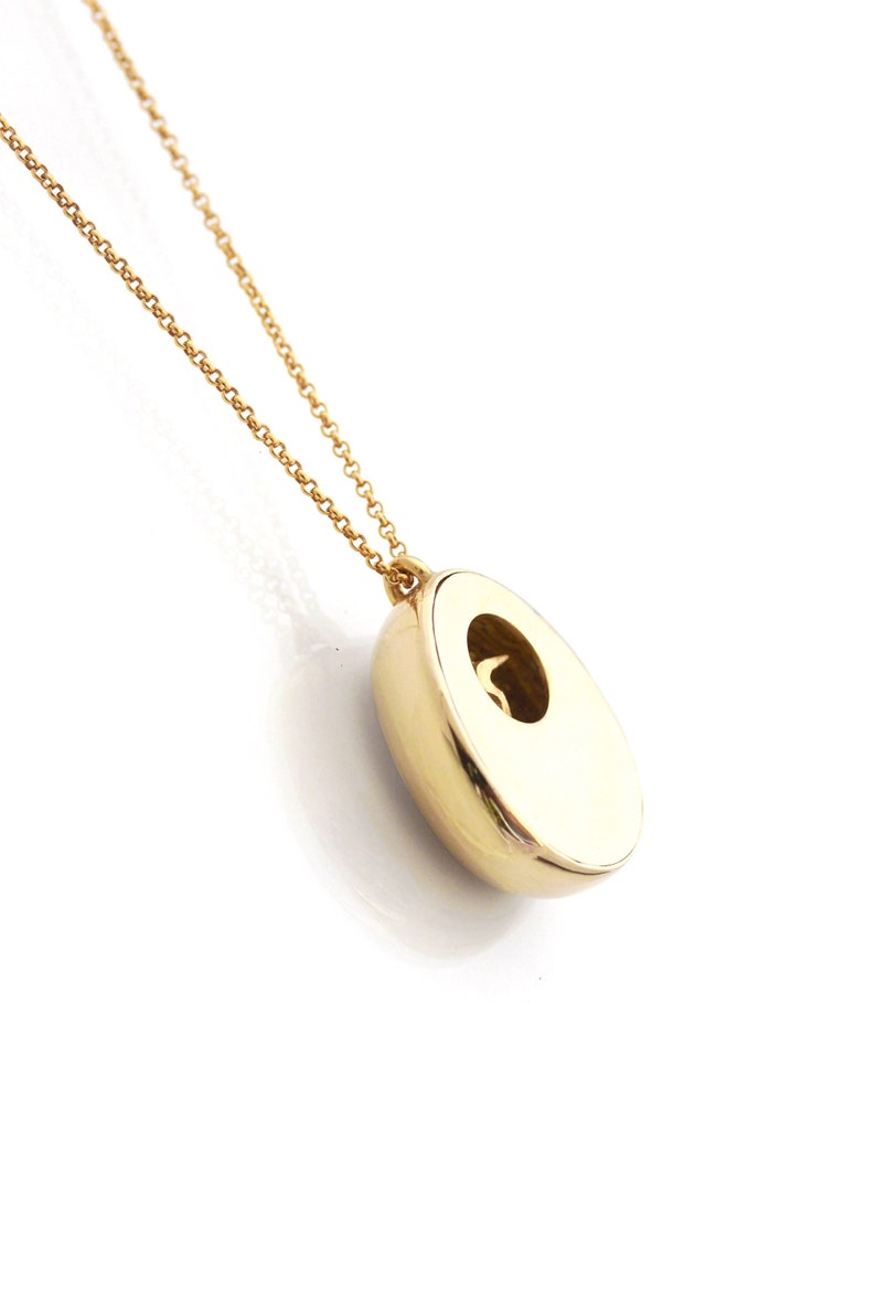 May include: A gold chain necklace with a round pendant. The pendant has a small opening in the center.