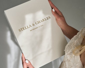 May include: White wedding album with gold lettering that reads "Stella & Charles September 18, 2024".