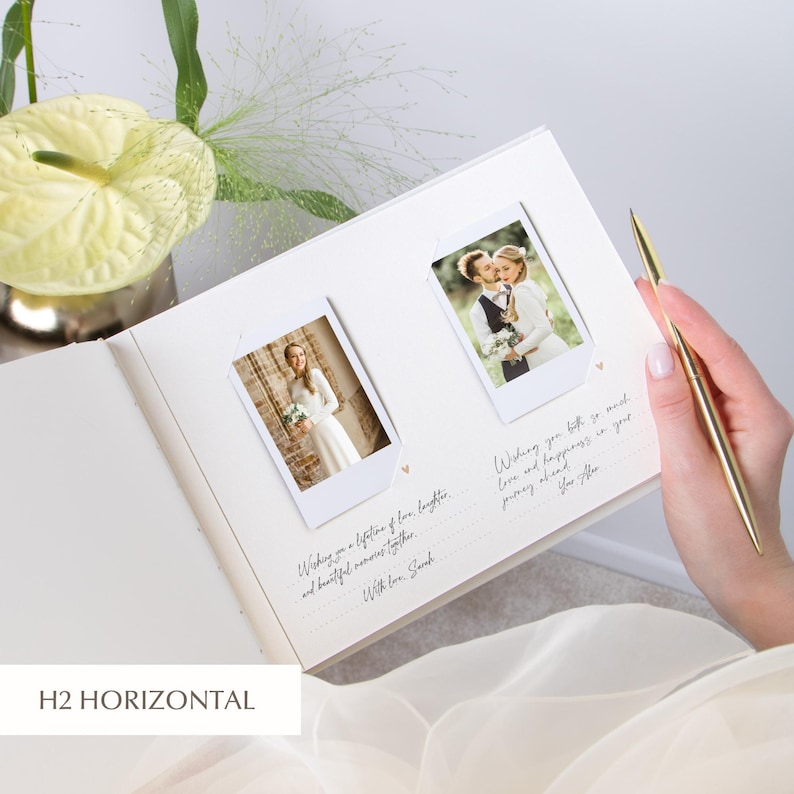 Open ivory wedding guest book held on the bride’s lap, two Instax/Polaroid prints mounted side‑by‑side in white photo corners, dotted lines with tiny heart icons for guest messages below each image; bride holding a gold pen, pale green flowers and airy greenery in the background.