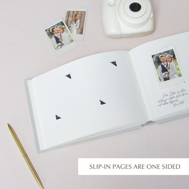 Inside slip-in wedding guest book showing one-sided photo pockets and handwritten message beside an Instax picture, sand album insert pages
