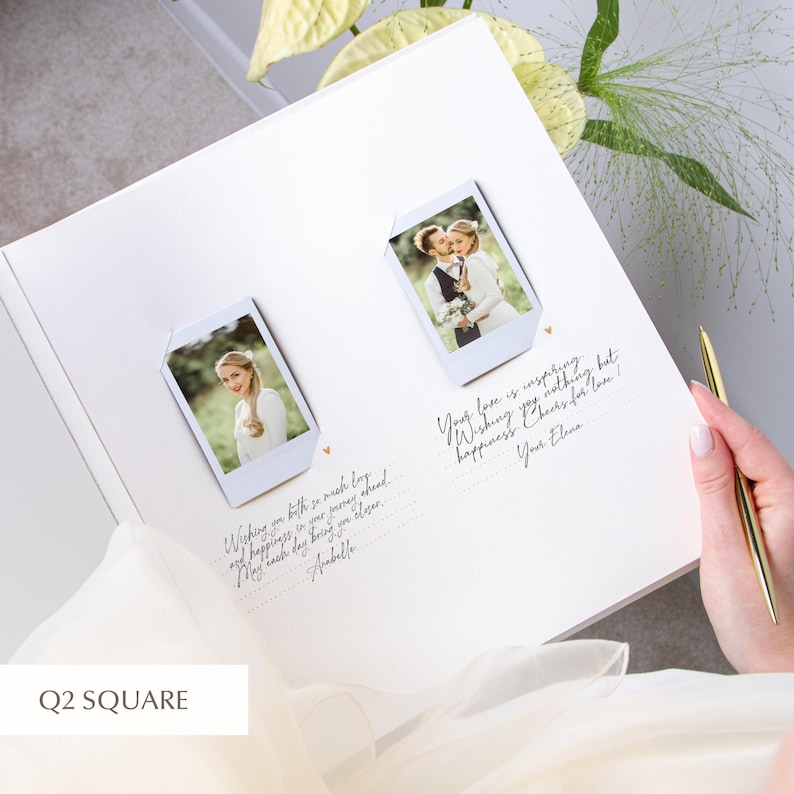 Bride holding an open wedding guest book on her lap; two instant photos mounted left and right with white corner holders, neat dotted guide lines and small heart icons for sign‑in notes; gold pen in hand and soft green floral arrangement nearby.
