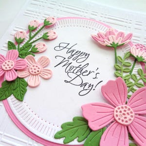 May include: A pink and green paper card with a circle of flowers and leaves around the text "Happy Mother's Day!"