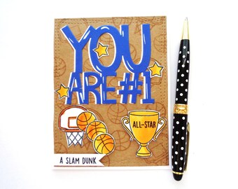 May include: A brown card with a blue and white "You Are #1" message. The card has a basketball theme with a basketball hoop, basketballs, and a trophy that says "All-Star". The card also says "A Slam Dunk" at the bottom.