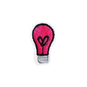 May include: A pink light bulb embroidered patch with a black outline. The patch is on a white background.