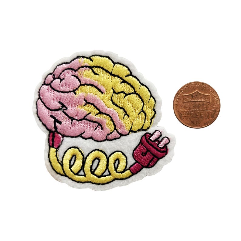 May include: An embroidered iron-on patch featuring a pink and yellow brain with a red and yellow electrical cord. The patch is about the size of a UK penny.