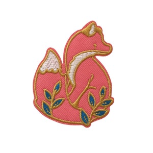May include: A pink embroidered patch of a fox with gold outlines and blue leaves. The fox is sitting with its tail curled around its body.