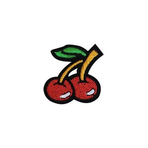 May include: Two red cherries with green stems and yellow leaves. The cherries are outlined in black.