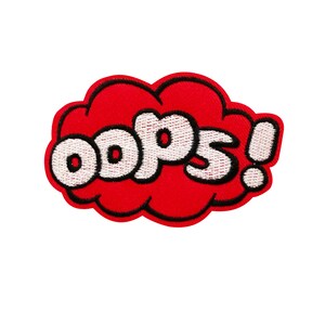 May include: Red and white embroidered patch with the word "oops!" in a comic book style speech bubble.