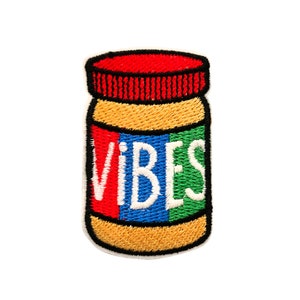 May include: A cartoon illustration of a peanut butter jar with the word "VIBES" written on the label in red, white, blue, and green letters.