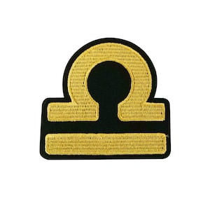 May include: Gold embroidered Libra zodiac sign patch on a black background.