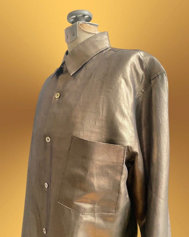 K&ouml;nnte beinhalten: Ein lang&auml;rmliges Hemd mit Kn&ouml;pfen in metallischem Silber mit einer einzigen Tasche auf der linken Seite.