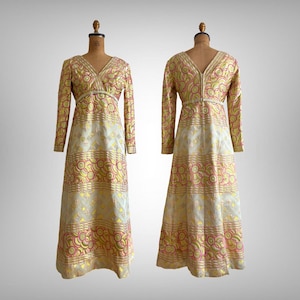 Puede incluir: Un vestido largo de manga larga con cuello en V y un patrón geométrico en tonos rosa, dorado y blanco.