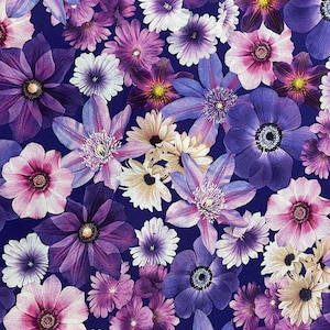 May include: A close-up of a fabric with a floral pattern. The fabric features a variety of purple, pink, and white flowers on a dark blue background.