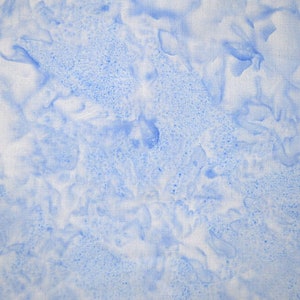 May include: A close-up of a fabric with a watercolor effect. The fabric has a white base with blue, cloud-like patterns and speckled details. The overall effect is soft and airy, resembling a cloudy sky.
