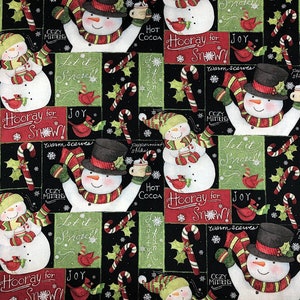 May include: A black fabric with a repeating pattern of snowmen, candy canes, holly, and snowflakes. The text "Let it Snow!" and "Hooray for Snow!" is repeated throughout the fabric.