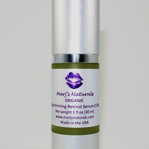 May include: A silver and green bottle of Marj's Naturals Organic Skin Firming Retinol Serum 2.5%. The label features a purple lip design and the text "Net weight 1 fl oz (30 ml)". The product is made in the USA.