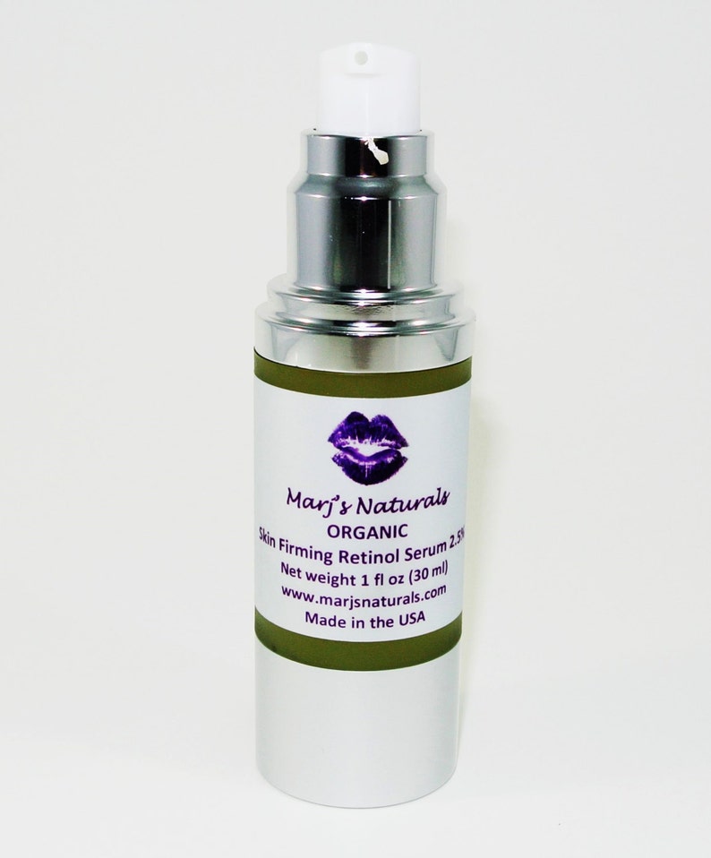 May include: A silver and white pump bottle of Marj's Naturals Organic Skin Firming Retinol Serum 2.5%. The label features a purple lip design and product information. Net weight is 1 fl oz (30 ml). Made in the USA.