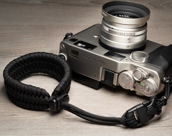 May include: A silver camera with a black leather strap and a silver lens with the text "Zeiss" on it.