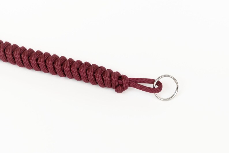 May include: A maroon paracord keychain with a silver metal ring.