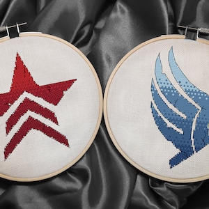 May include: Two embroidered hoops with different designs. The left hoop features a red star with a white chevron design. The right hoop features a blue wing with a white outline.