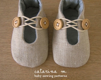 Op de afbeelding: Een paar beige baby-schoentjes van linnen met witte veters en houten knoopaccenten. De schoentjes hebben een blauw-wit gestreepte voering.