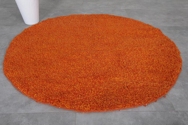 May include: A round, orange, fluffy rug with a soft, plush texture.