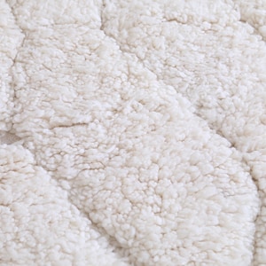 May include: Close-up of a white, fluffy, textured fabric with a wavy pattern. The fabric is soft and plush, resembling a sheepskin rug.