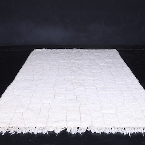 May include: A white shag rug with a woven pattern. The rug has a fringe border.