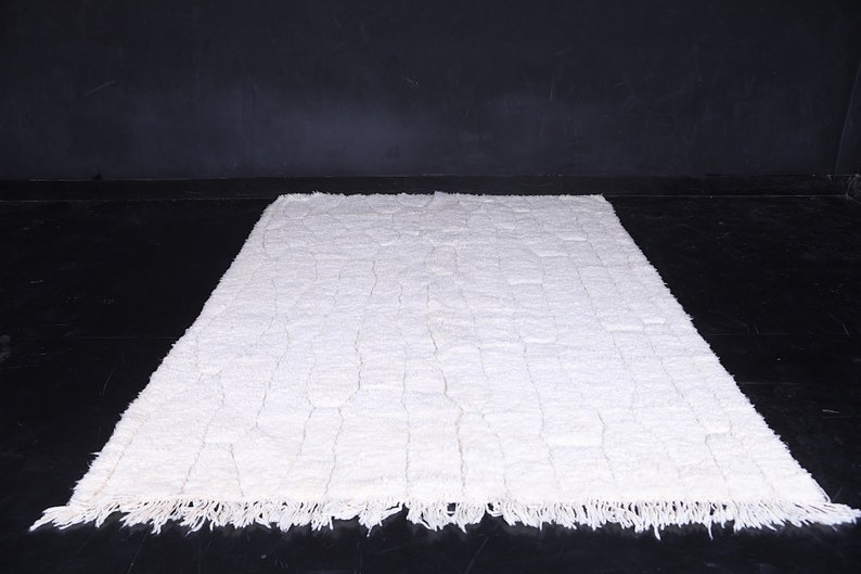 May include: A white shag rug with a woven pattern. The rug has a fringe border.