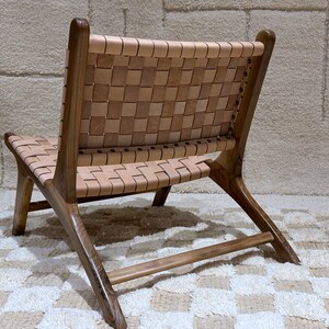 May include: A brown wooden chair with a woven leather seat and back. The chair has a simple, modern design and is ideal for a living room or dining room.