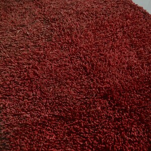May include: A close-up of a deep red bath mat with a soft, plush texture.