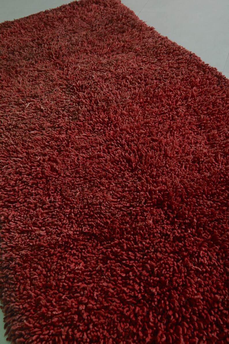 May include: A close-up of a deep red bath mat with a soft, plush texture.