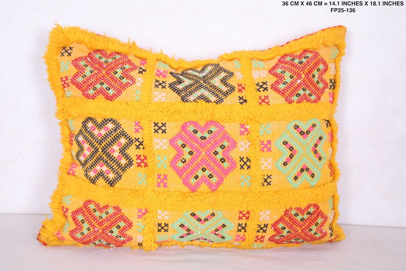 K&ouml;nnte beinhalten: Gelbes Kissen mit geometrischem Muster in Rot, Rosa, Gr&uuml;n und Schwarz. Das Kissen hat einen Fransenrand und misst 36 cm x 46 cm.
