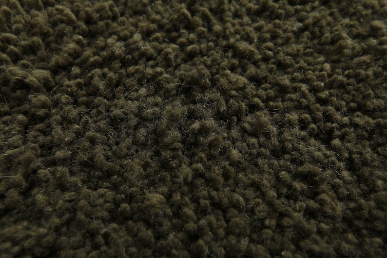 May include: Close-up of a dark green fuzzy fabric texture. The fabric has a soft, plush feel and is perfect for creating cozy and comfortable items.