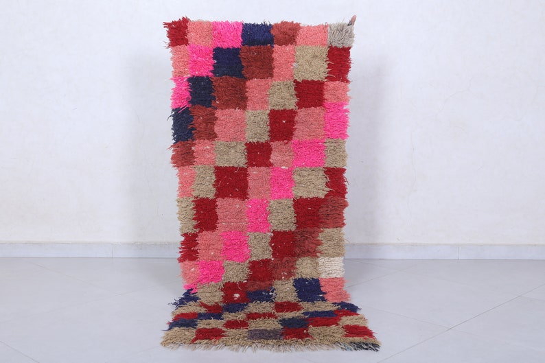May include: A pink, red, brown and blue checkered rug with a shaggy texture. The rug is made of wool and is perfect for adding a touch of colour and texture to any room.
