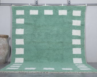 Könnte beinhalten: Ein grüner Teppich mit einem weißen Rand aus Quadraten. Der Teppich hat eine weiche, flauschige Textur.