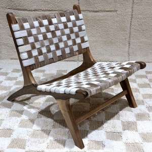 May include: A wooden chair with a woven leather seat and back. The leather is a checkered pattern of white and brown.