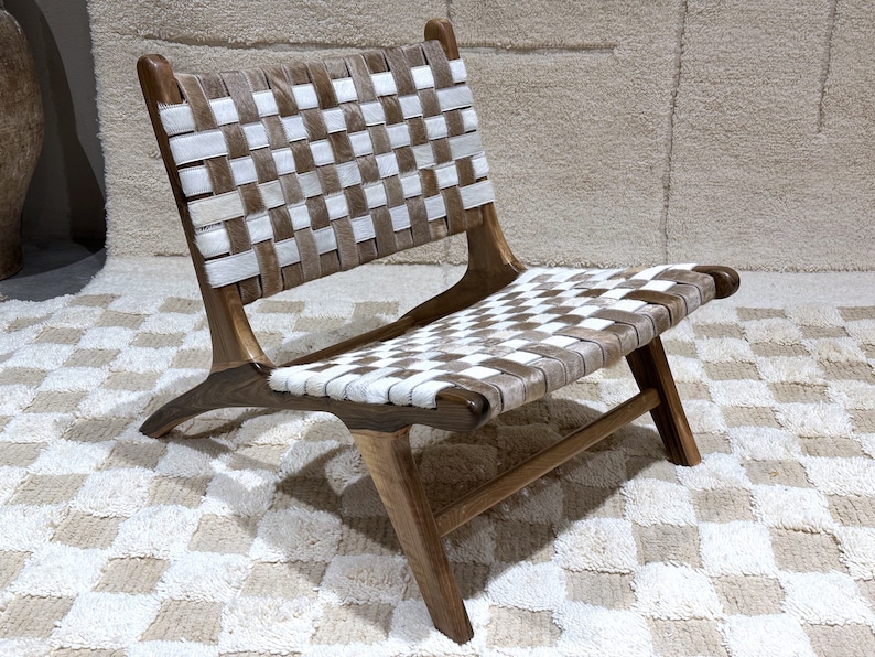 May include: A wooden chair with a woven leather seat and back. The leather is a checkered pattern of white and brown.